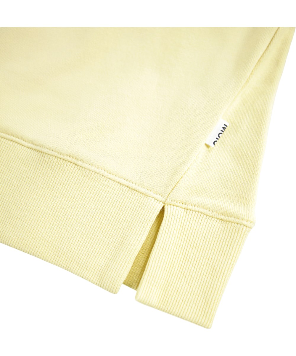 Marilee - Mellow Yellow - Ljusgul tröja för barn i ekologisk bomull med en paljettregnbåge.