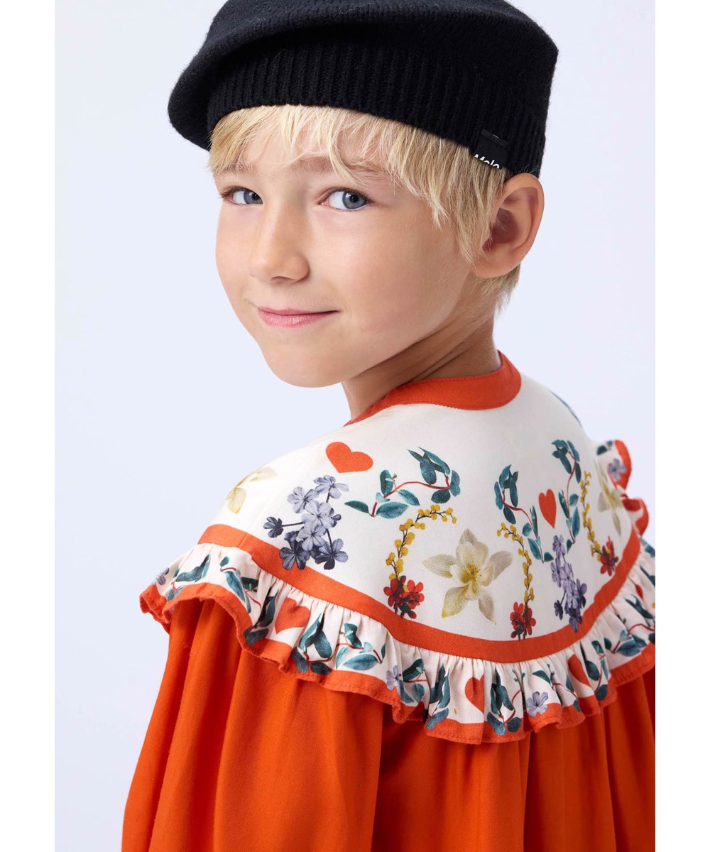 Cibbe - Alpine Flora - Orange knee-length dress for children made of viscose with a print of flowers on the yoke.