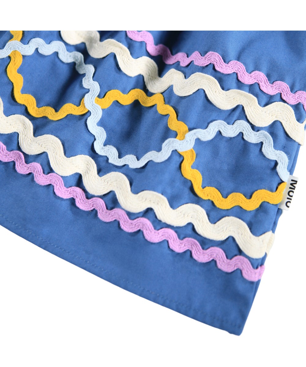 Ciris - Mystic Blue - Blue dress for children made of organic cotton with colorful zig-zag ribbons as a nice detail.