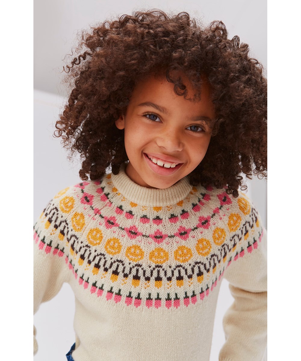 Gretchen - Nordic Forest - Light coloured knit top with a yellow and pink smiley face pattern 