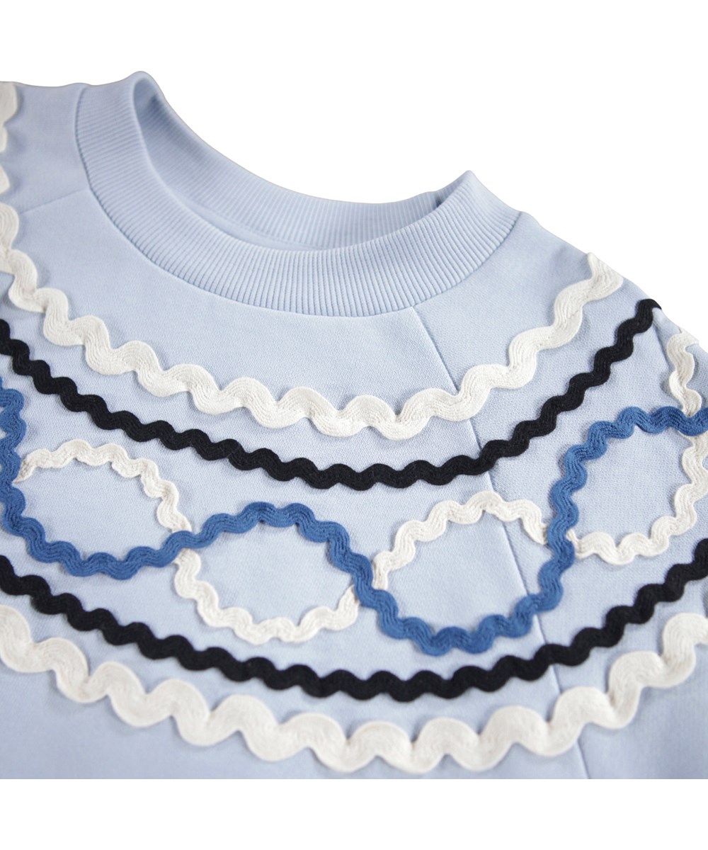 Marilyn - Blue Moon - Light blue sweatshirt for children made of organic cotton with a colorful pattern of sewn-on ribbons.