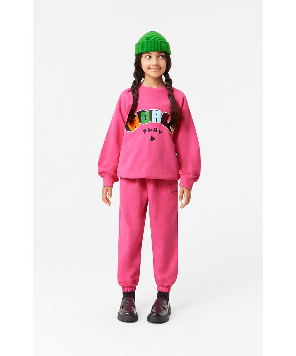 Monti - Shocking Pink - Soft pink organic cotton sweatshirt with embroidered 'World Play' artwork.