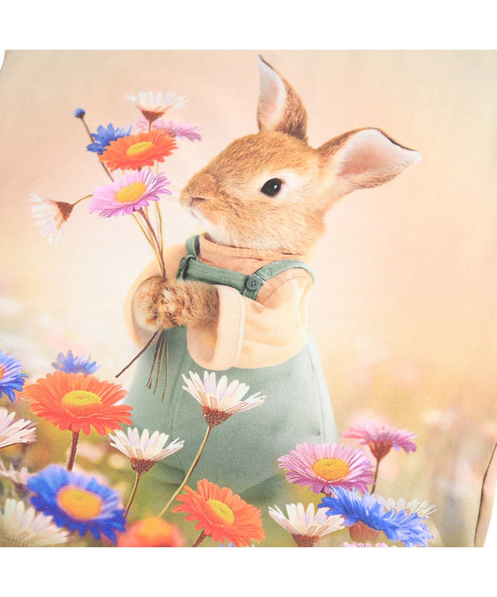 Ragnhilde - Bunny Rabbit - Light orange, short-sleeved T-shirt for children made of organic cotton with a front print of a rabbit in a colorful flower field.