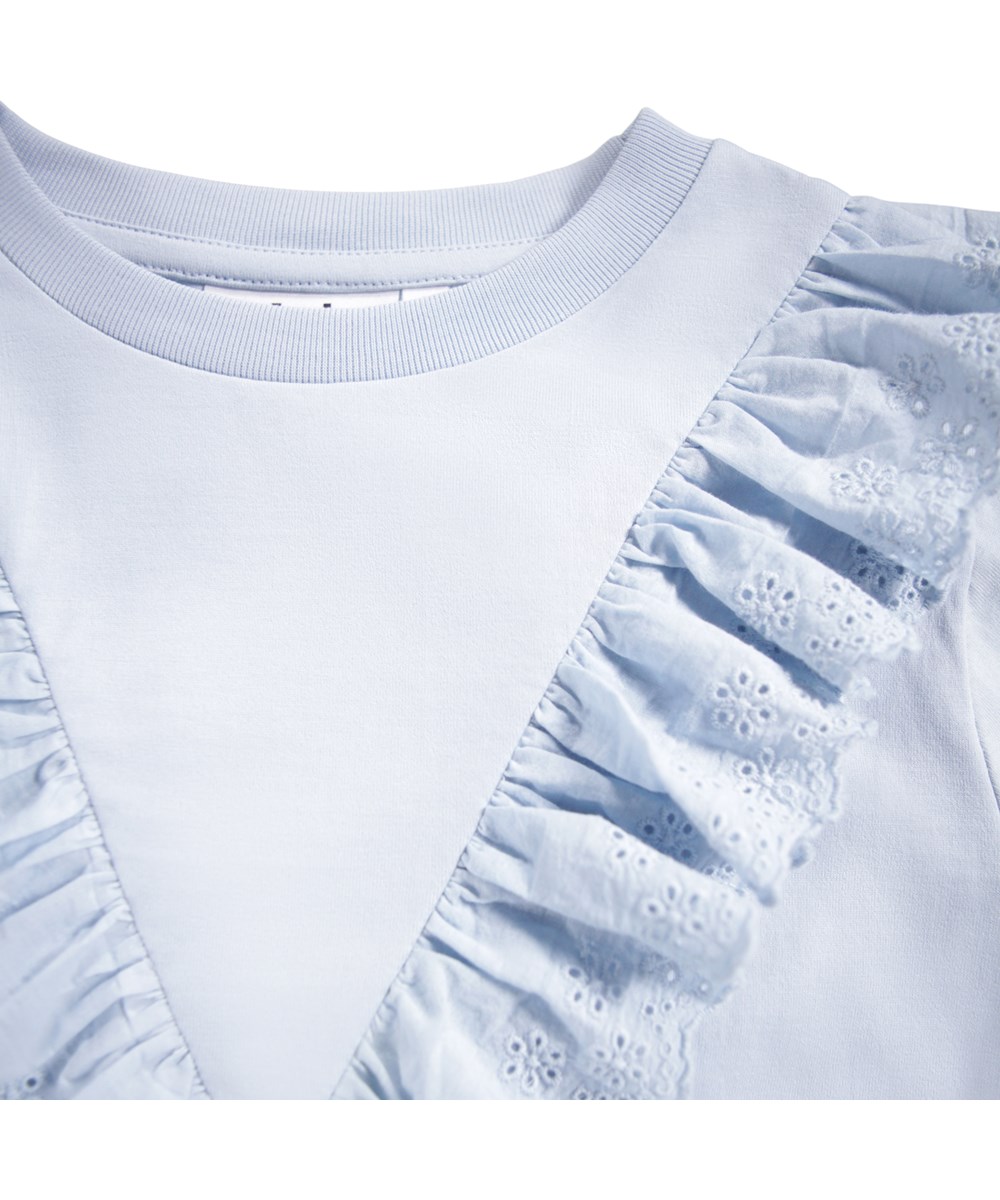 Rheta - Blue Moon - Light blue, long-sleeved top for children made of organic cotton with a round neck and ribbed edge and a ruffled edge in embroidery anglaise.
