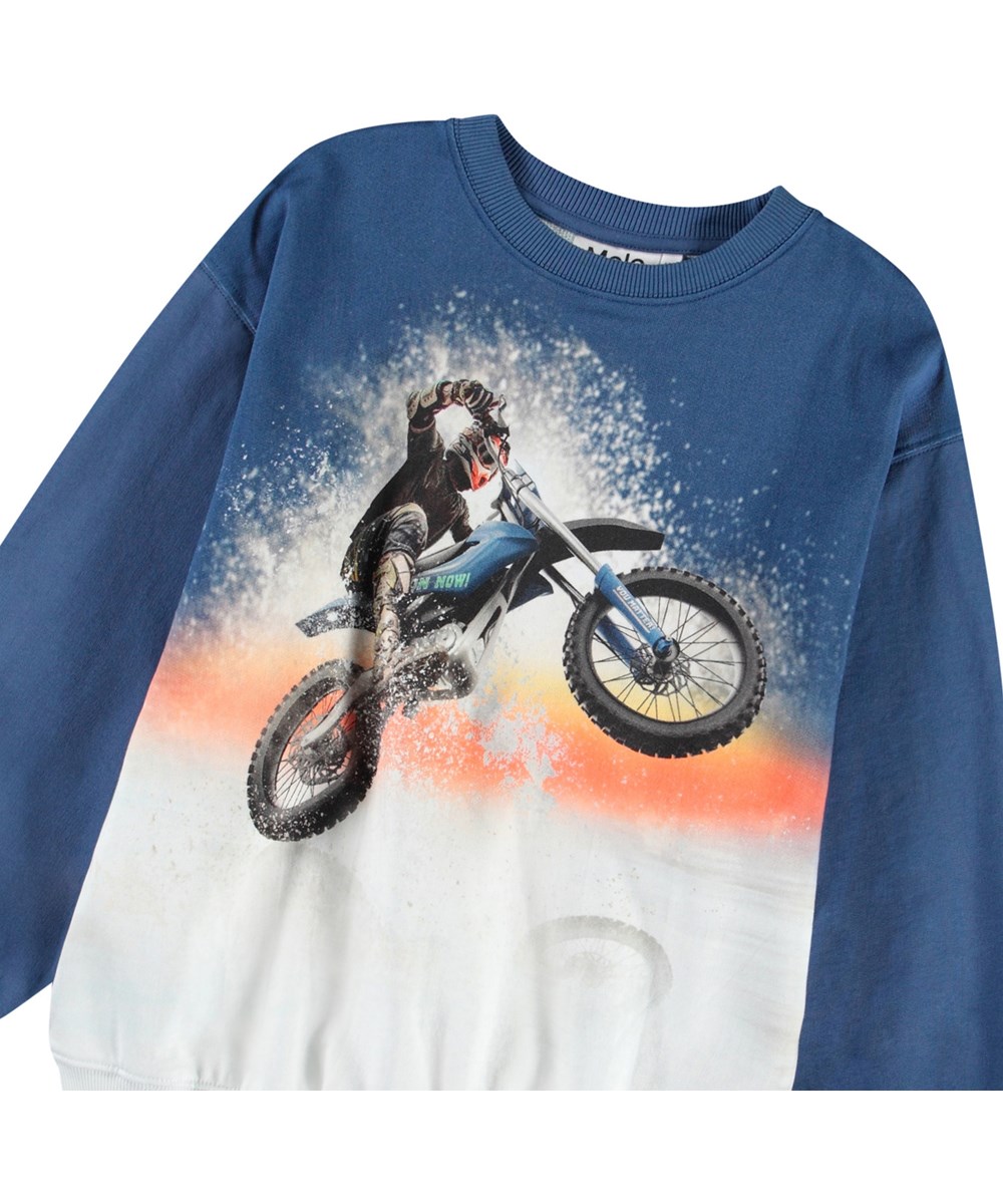 Monti - Wheelie Blue - Blauwe en witte kindersweater van zacht biologisch katoen met print en ribboord rond de hals, mouwen en onderkant.