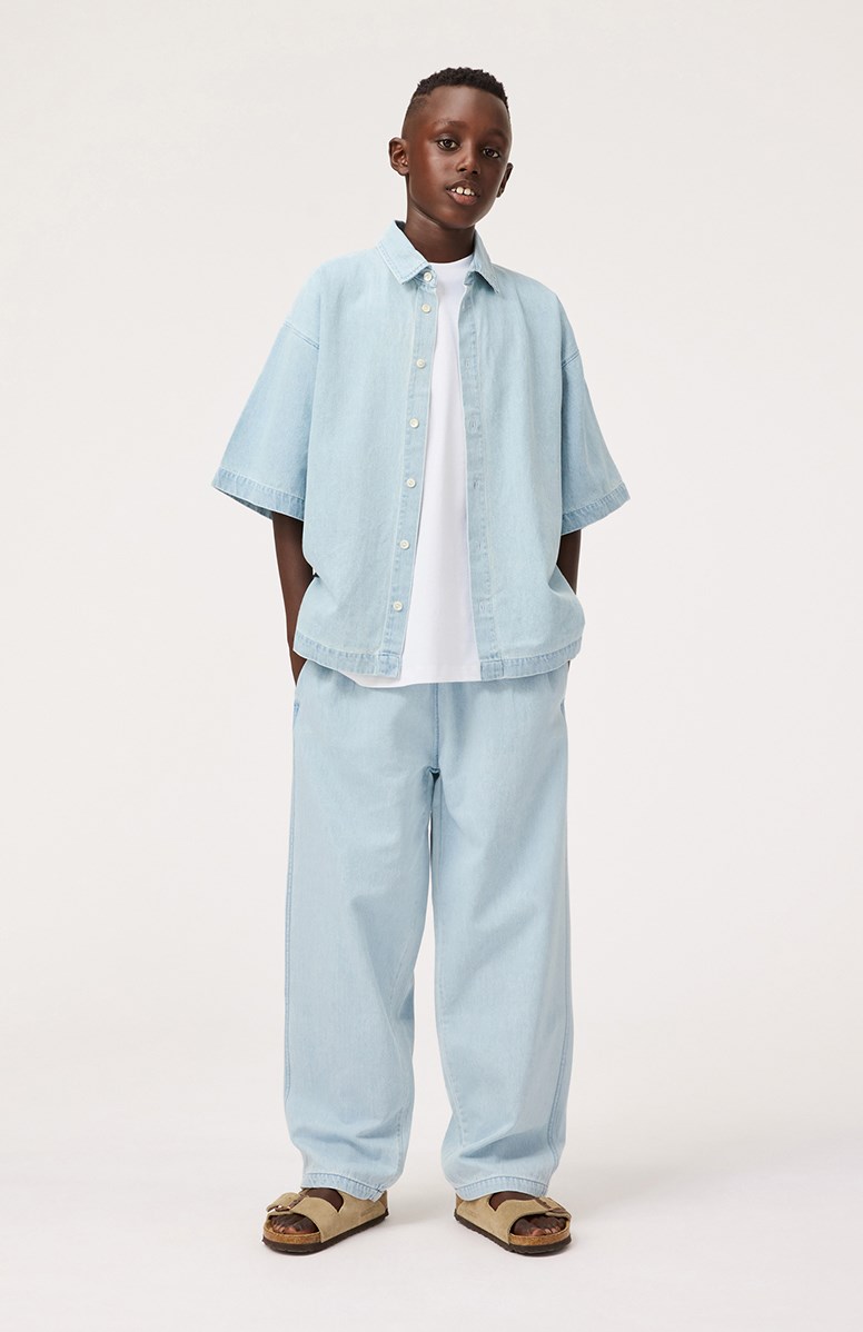 Richie - Misty Denim - Hellblaues Jeanshemd mit Druck für Kinder aus weicher Öko-Baumwolle mit weiten T-Shirt-Ärmeln, klassischem Hemdkragen und Knopfverschluss auf der Vorderseite.