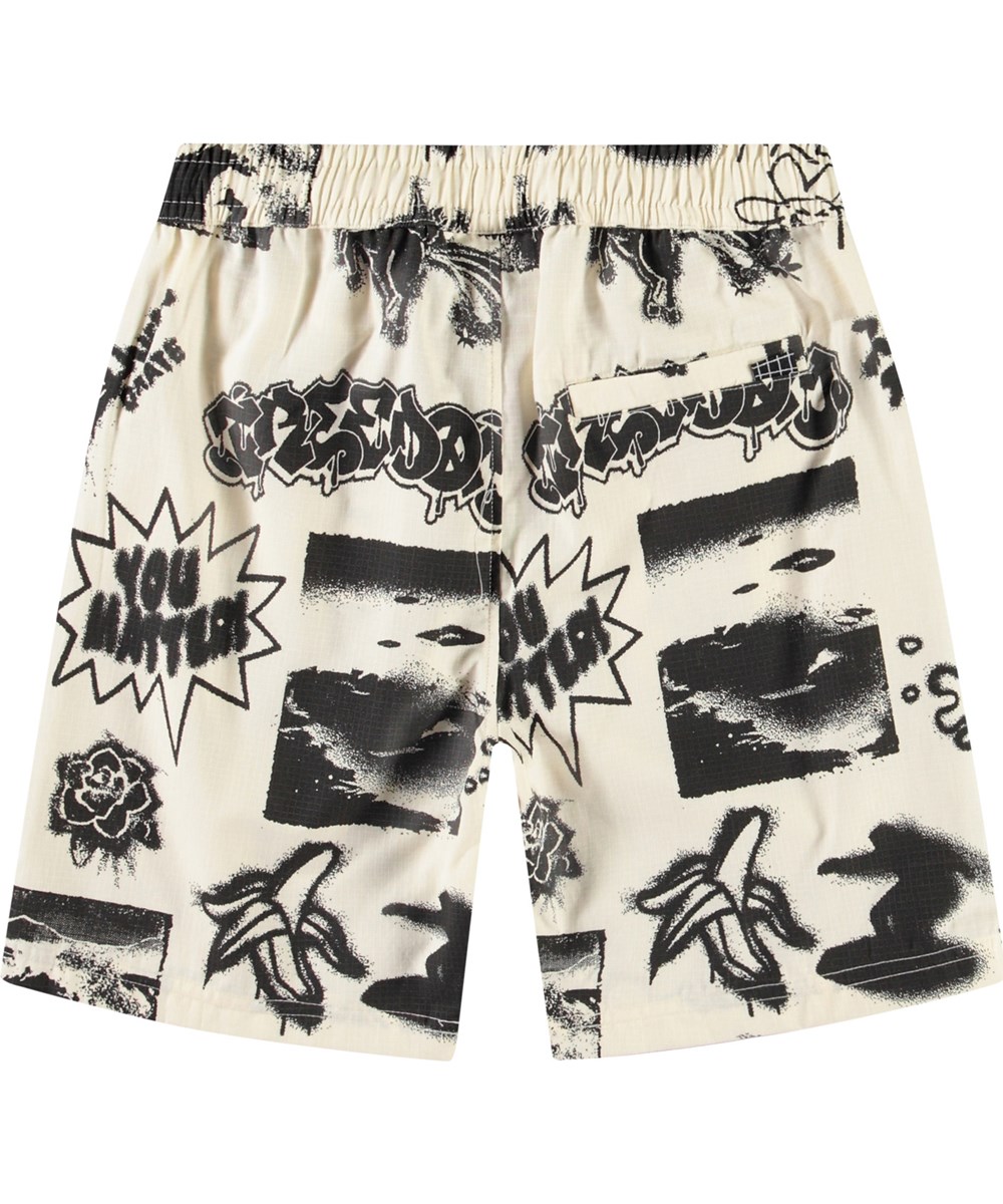 Avart - Art Mix - Knielange Shorts aus Öko-Baumwolle für Kinder. Diese Shorts sind beige mit einem Skate-inspirierten Druck und coolen Statements.
