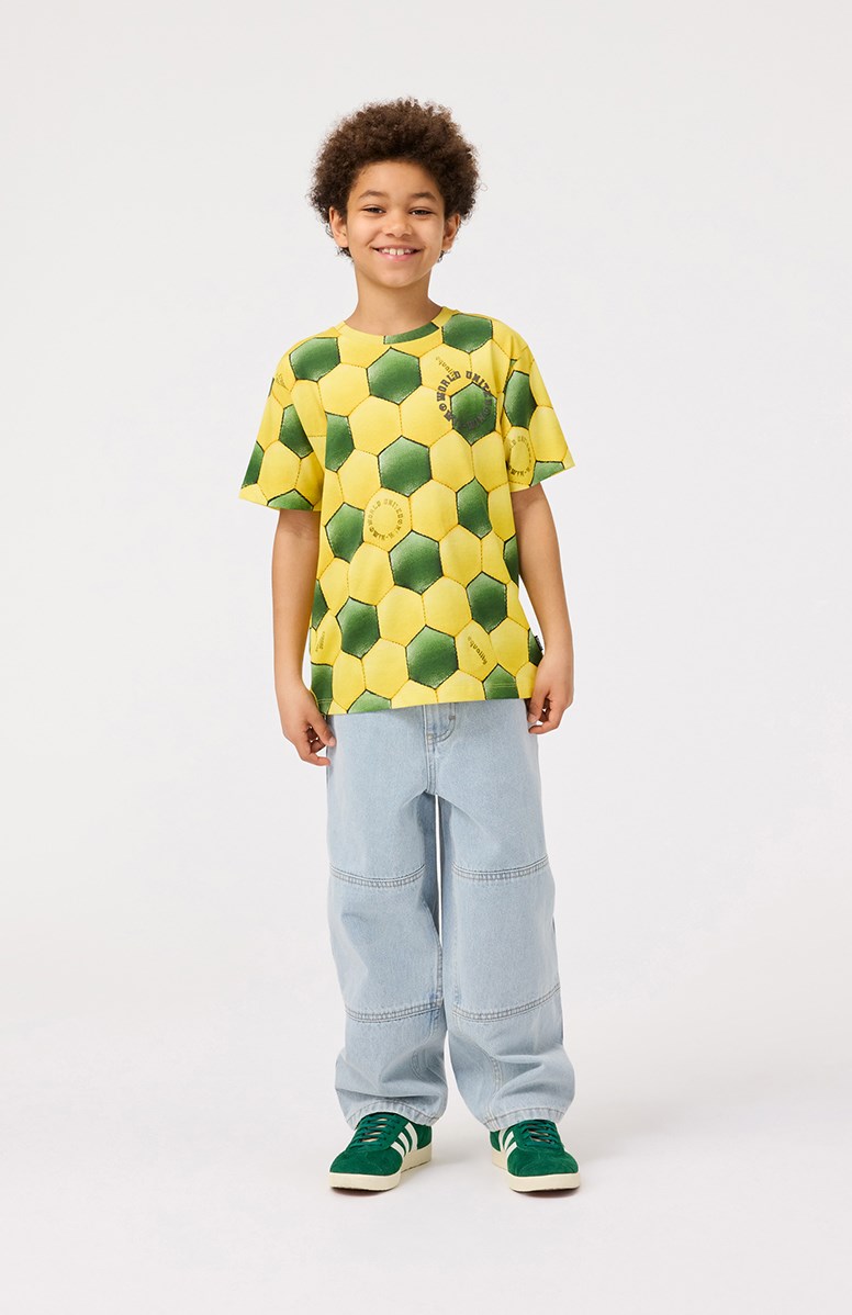 Riley - Football Sunbeam - Gelbes und grünes T-Shirt mit Druck für Kinder aus weicher Öko-Baumwolle mit kurzen Ärmeln und geripptem Ausschnitt.