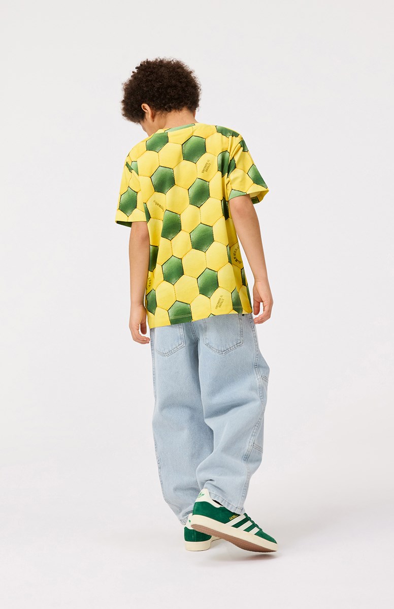 Riley - Football Sunbeam - Gelbes und grünes T-Shirt mit Druck für Kinder aus weicher Öko-Baumwolle mit kurzen Ärmeln und geripptem Ausschnitt.