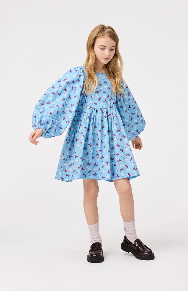 Caiosi - Giddy-Up - Knielanges hellblaues Kleid für Kinder aus einer weichen Baumwollmischung mit einem Allover-Print von Pferden in burgunderrot und weißen Farben.