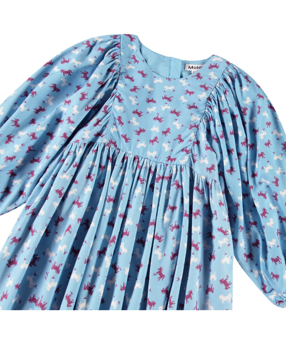 Caiosi - Giddy-Up - Knielanges hellblaues Kleid für Kinder aus einer weichen Baumwollmischung mit einem Allover-Print von Pferden in burgunderrot und weißen Farben.