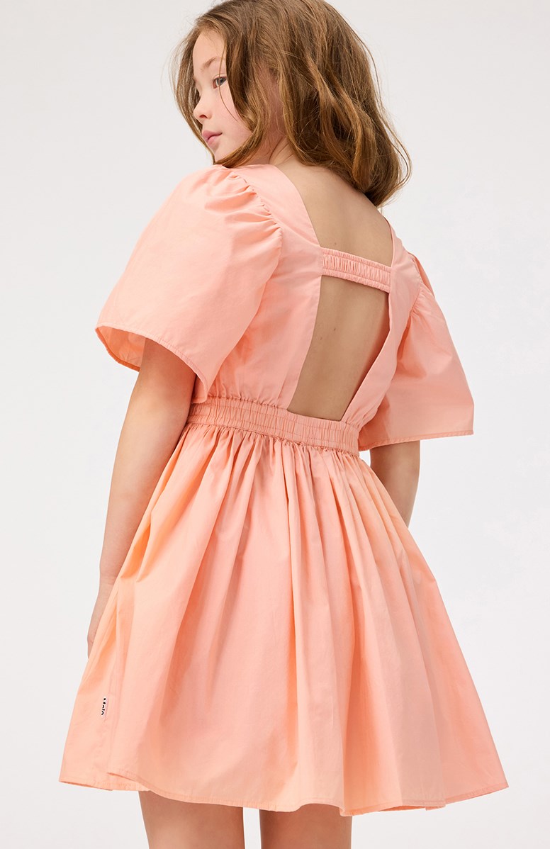 Cally - Peach - Leichtes orangefarbenes knielanges Kleid für Kinder aus Öko-Baumwolle mit einem runden Ausschnitt.