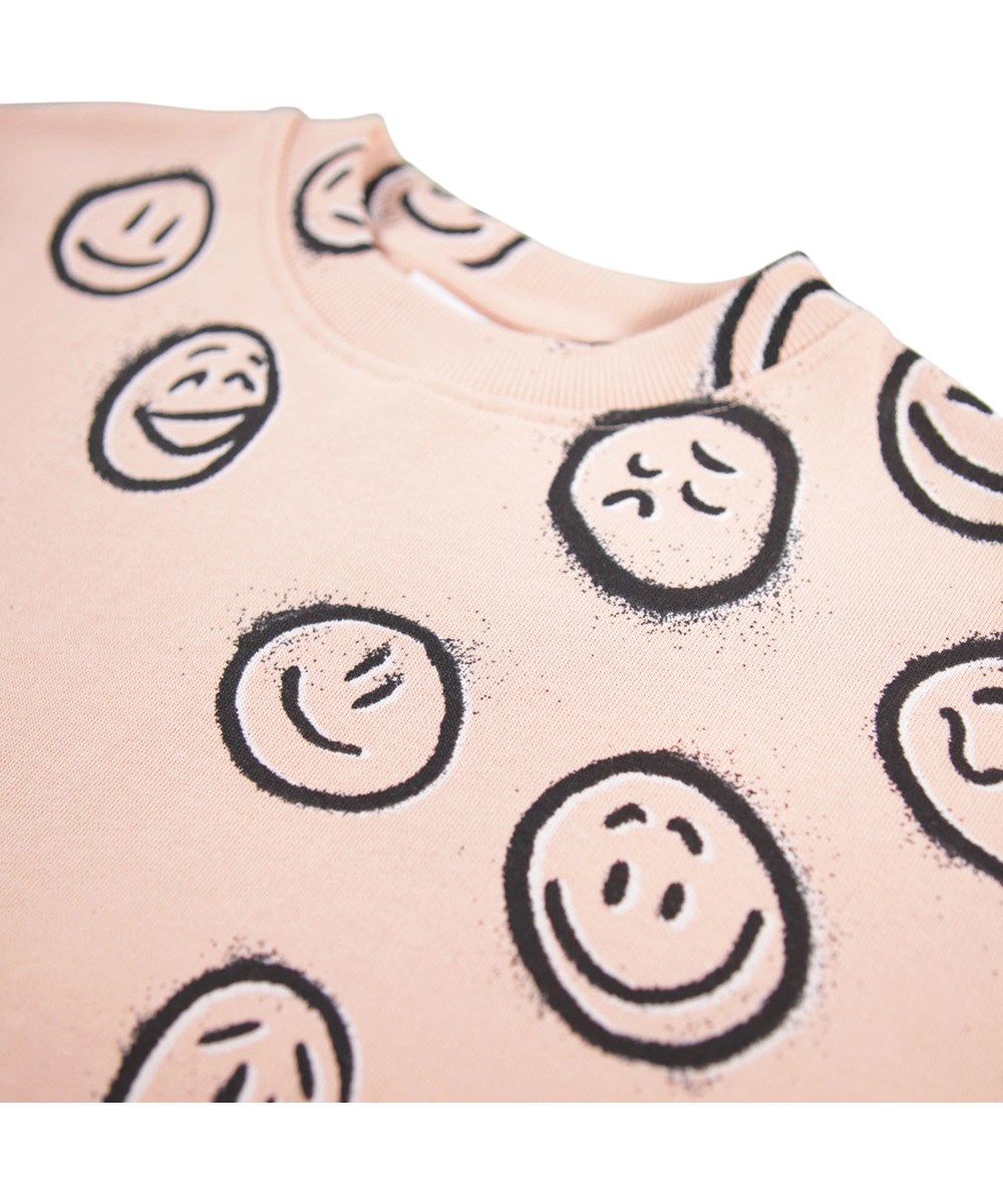 Cherice - Rose Cloud Moods - Rosa Sweatshirt-Kleid für Kinder aus weicher Öko-Baumwolle mit einem Druck von Gesichtern in verschiedenen Stimmungen.