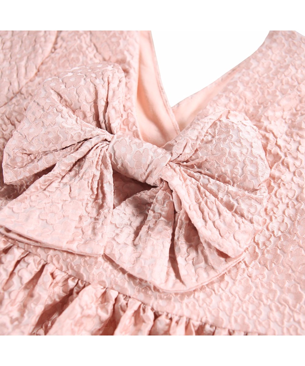 Coco - Foxglove Light - Voluminöses rosa Kleid für Kinder mit einem Jacquard-Blumenmuster und einer großen Schleife am Rücken.