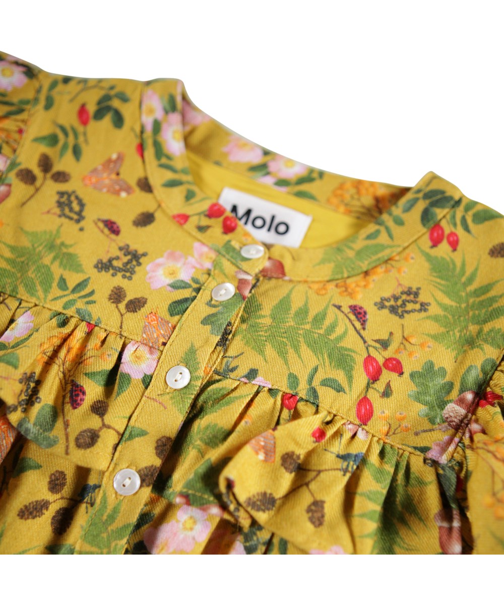 Constance - Foraging - Langärmeliges gelbes Kleid für Kinder mit Rüschen-Details und einem Druck von Blättern, Blumen und Nüssen.