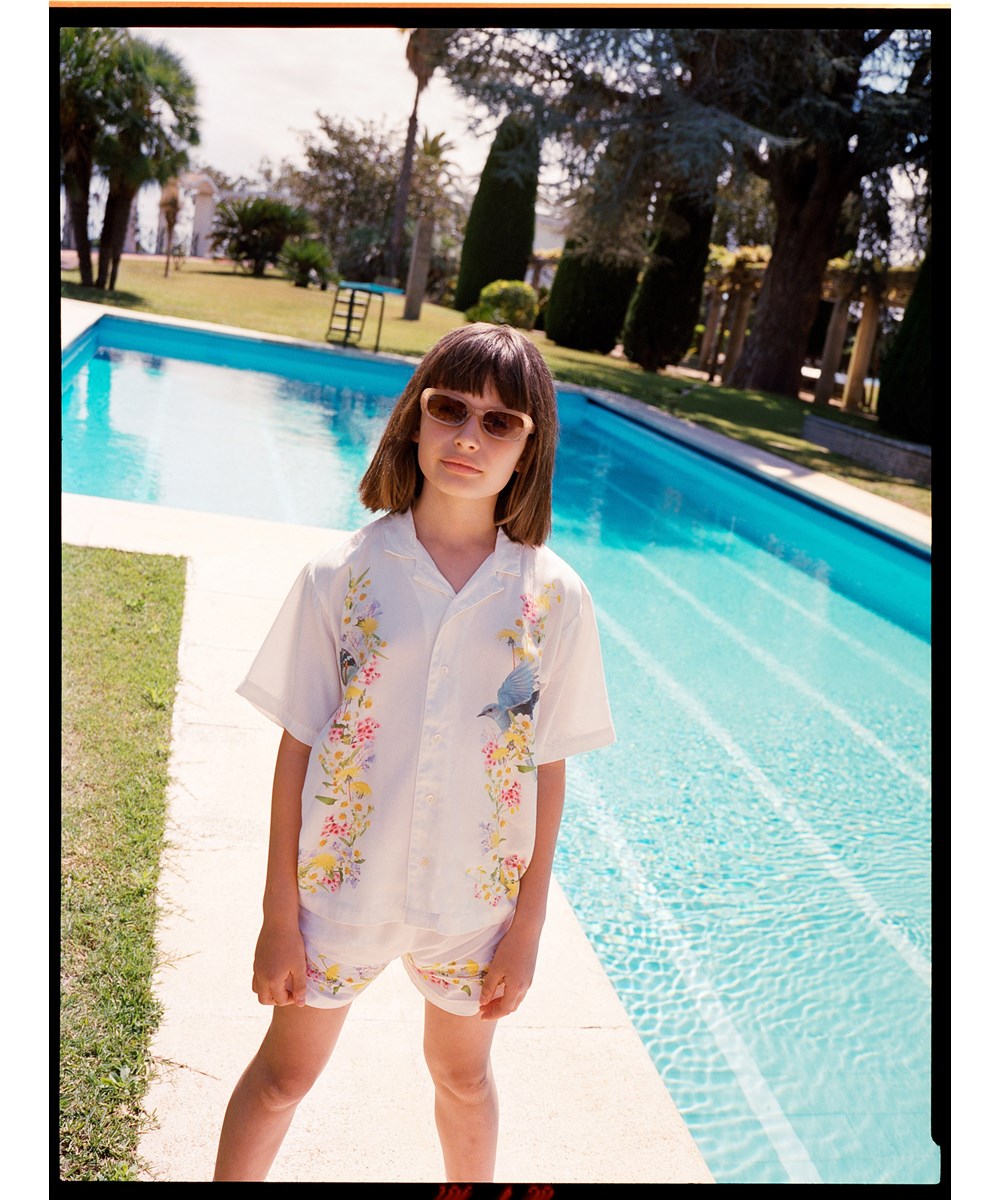 Adore - Picturesque - Weiße kurze lockere Shorts aus Viskose für Kinder mit Blumenmuster entlang des unteren Saums für Kinder.