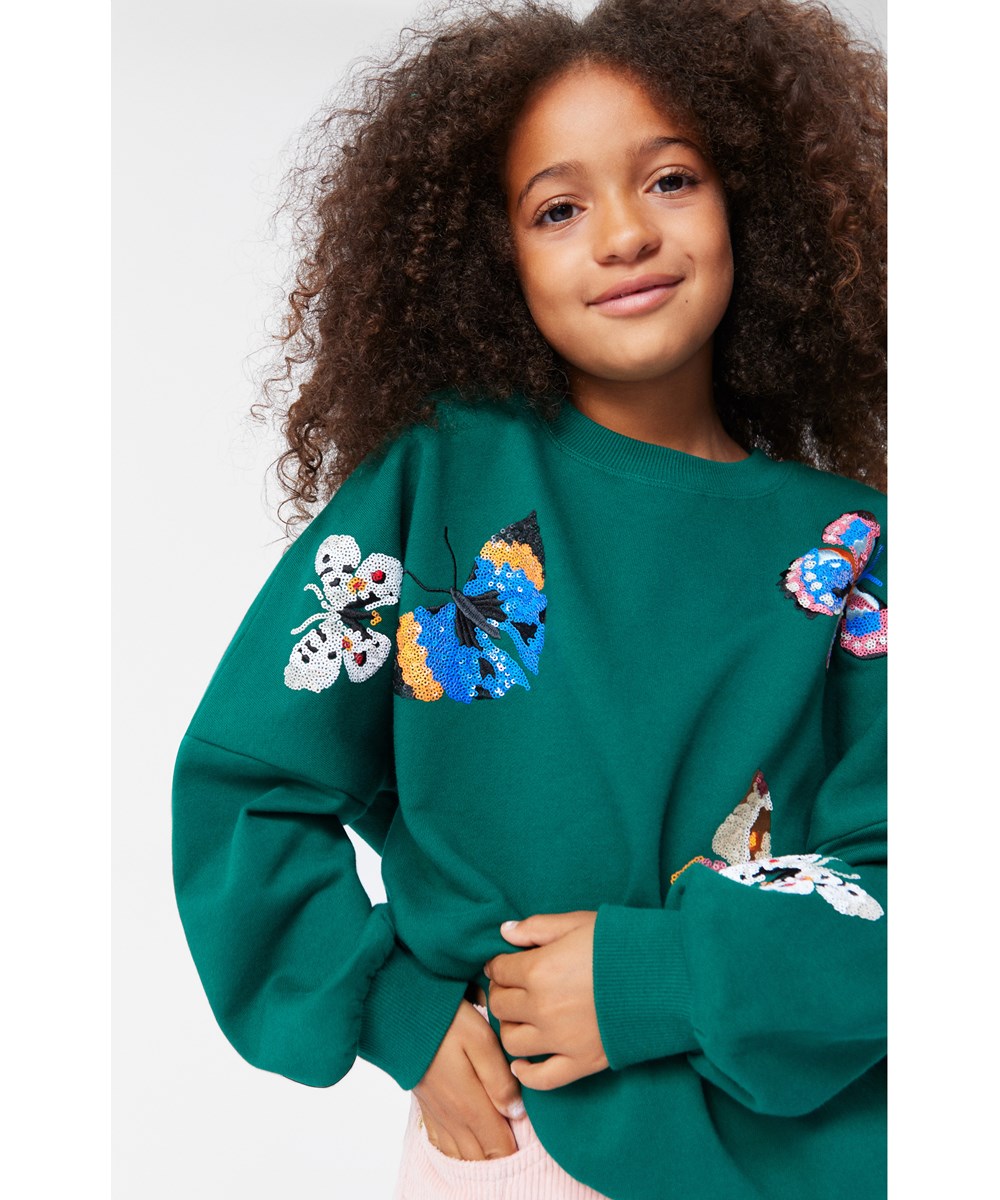 Marika - Aventurine - Flaschengrünes Sweatshirt aus weicher Öko-Baumwolle mit mehrfarbigen Paillettenstickereien von Schmetterlingen.
