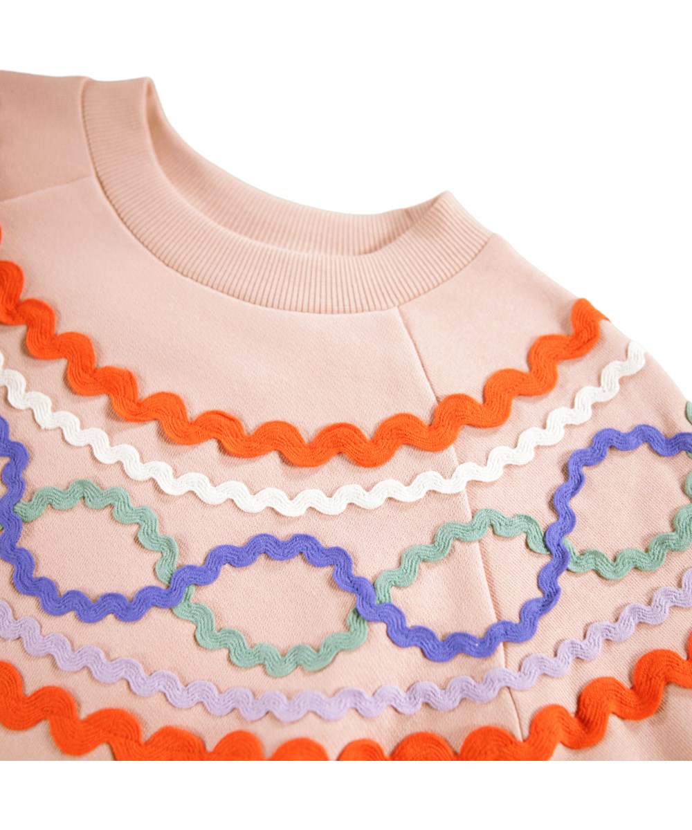 Marilyn - Rose Cloud - Rosa Sweatshirt für Kinder aus Öko-Baumwolle mit einem bunten Muster aus aufgenähten Bändern.