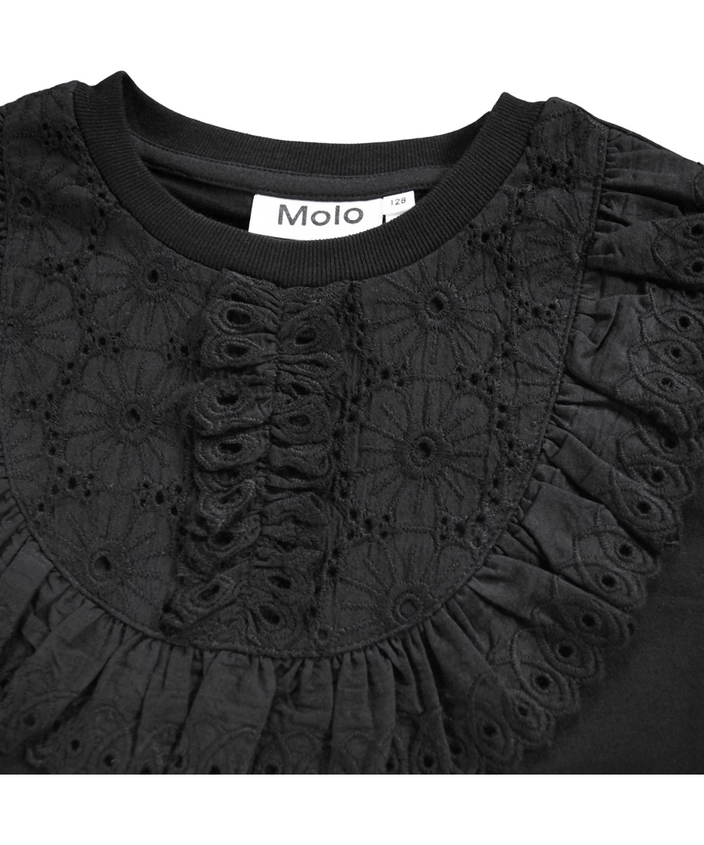 Rena - Black - Schwarze langärmelige Bluse für Kinder aus weicher Bio-Baumwolle mit Rundhalsausschnitt, gewelltem Saum und Stickerei im Anglaise-Stil.