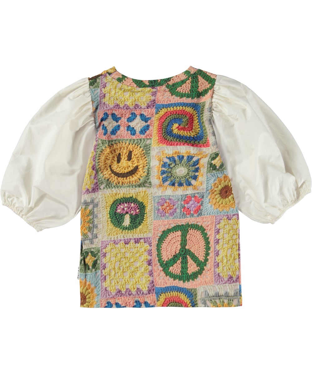 Rica - Crochet Vibe - Mehrfarbige Öko-Bluse mit Häkeldruck und weißen Puffärmeln.