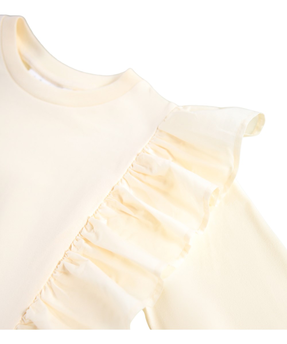 Rith - Buttercream - Off-White Langarmshirt für Kinder aus Bio-Baumwolle mit Rundhalsausschnitt und Rüschen.