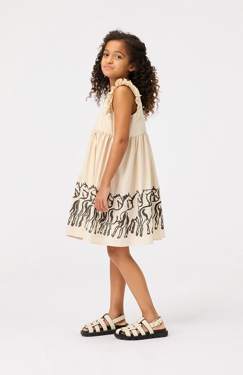 Cicely - Horse Border - Beige knielange kinderjurk van biologisch katoen met ruches rond de armsgaten.