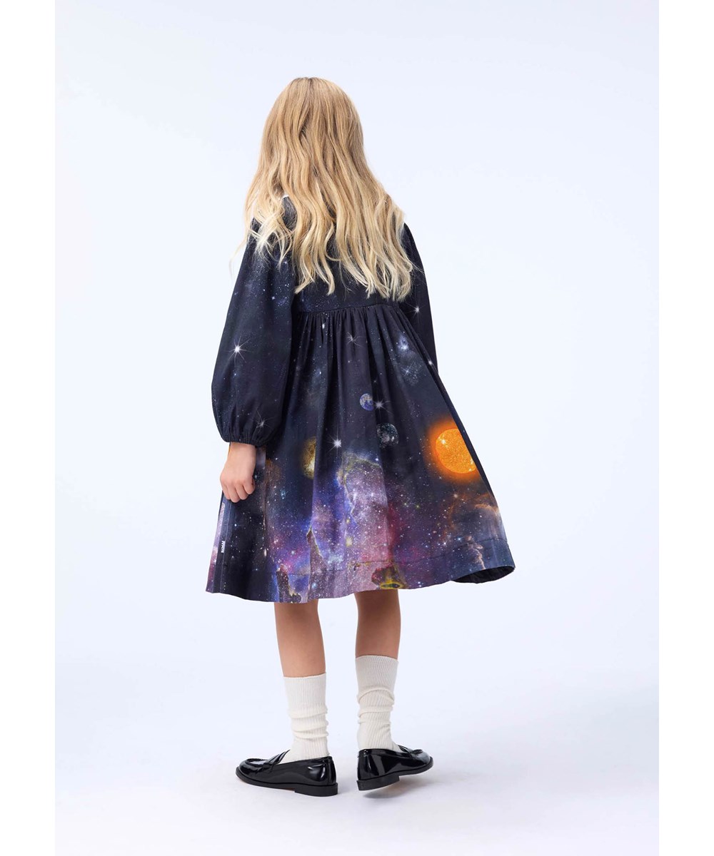 Crystal - Made Of Stardust - Knielange donkere kinderjurk gemaakt van biologisch katoen met een print van het heelal en planeten.