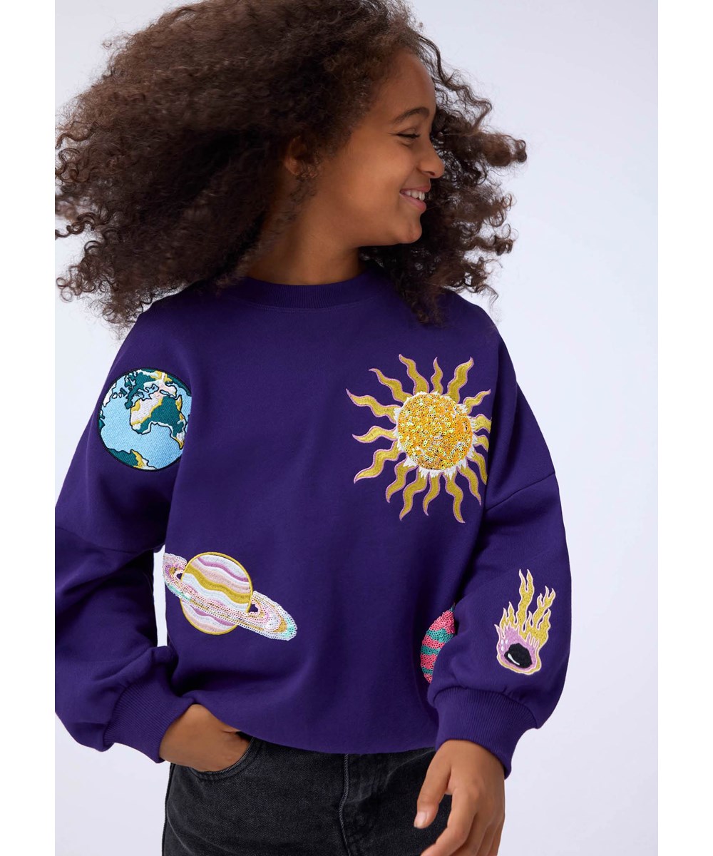 Marika - Sparkle Space - Paarse kindersweater gemaakt van biologisch katoen met een borduursel van de ruimte.
