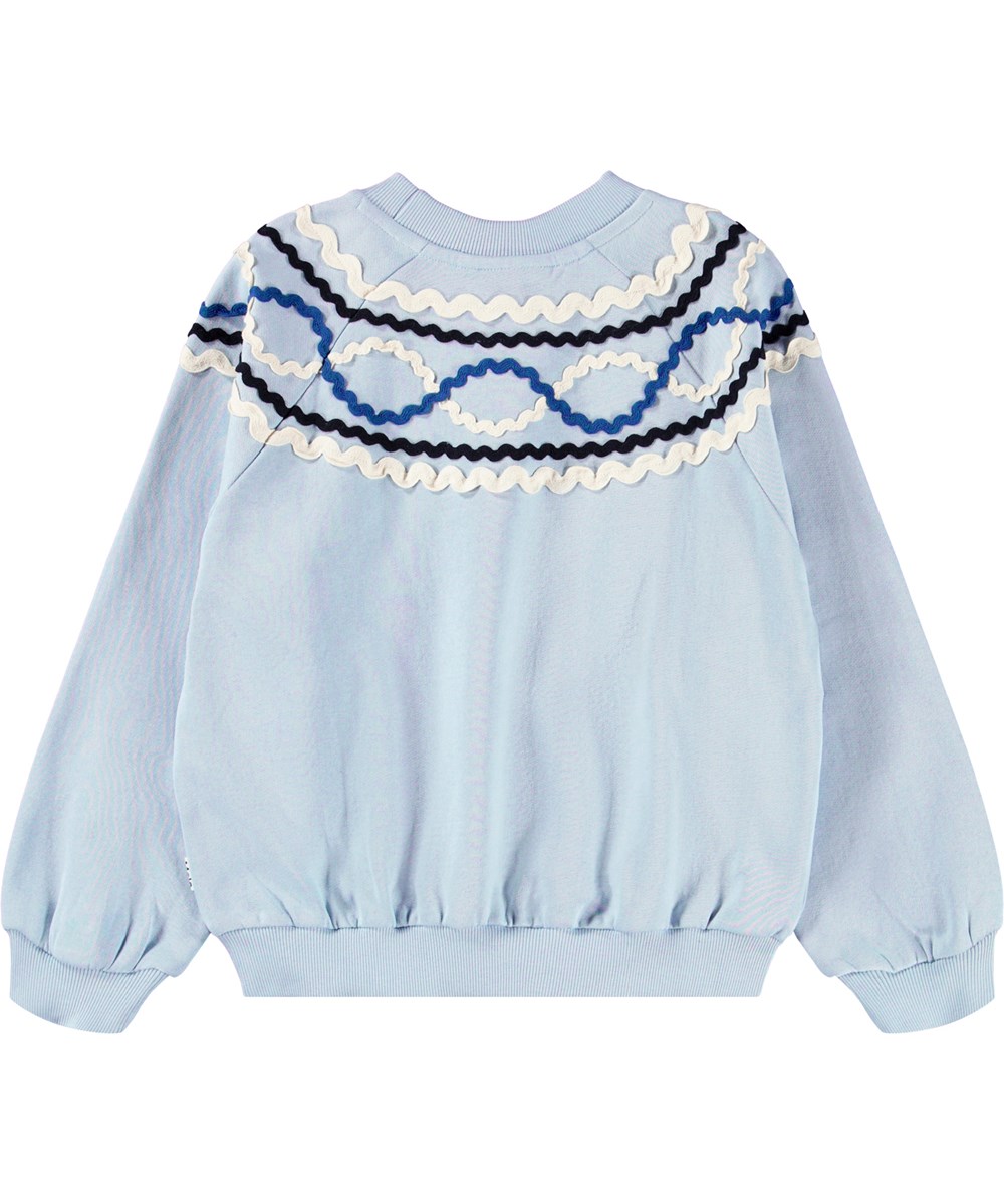 Marilyn - Blue Moon - Lichtblauwe kindersweater gemaakt van biologisch katoen met een kleurrijk patroon van opgenaaide linten.