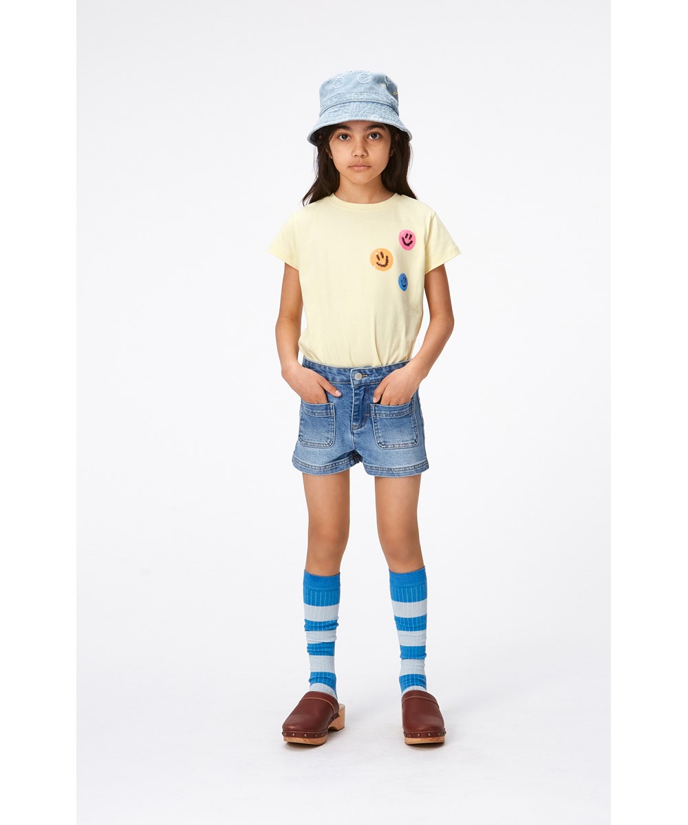 Ranva - Pale Dawn - Pastelgele t-shirt van biologisch katoen met op de borst drie kleine geborduurde smiley's van pailletten 