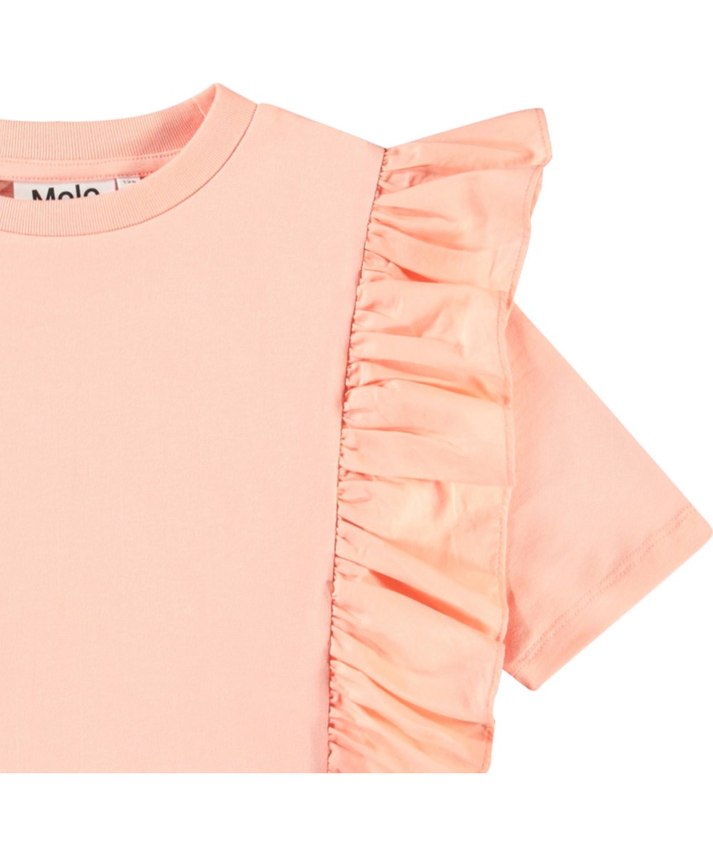 Riva - Peach - Lichtoranje kinder t-shirt in zacht biologische katoen met ribboord rond de hals en ruches.