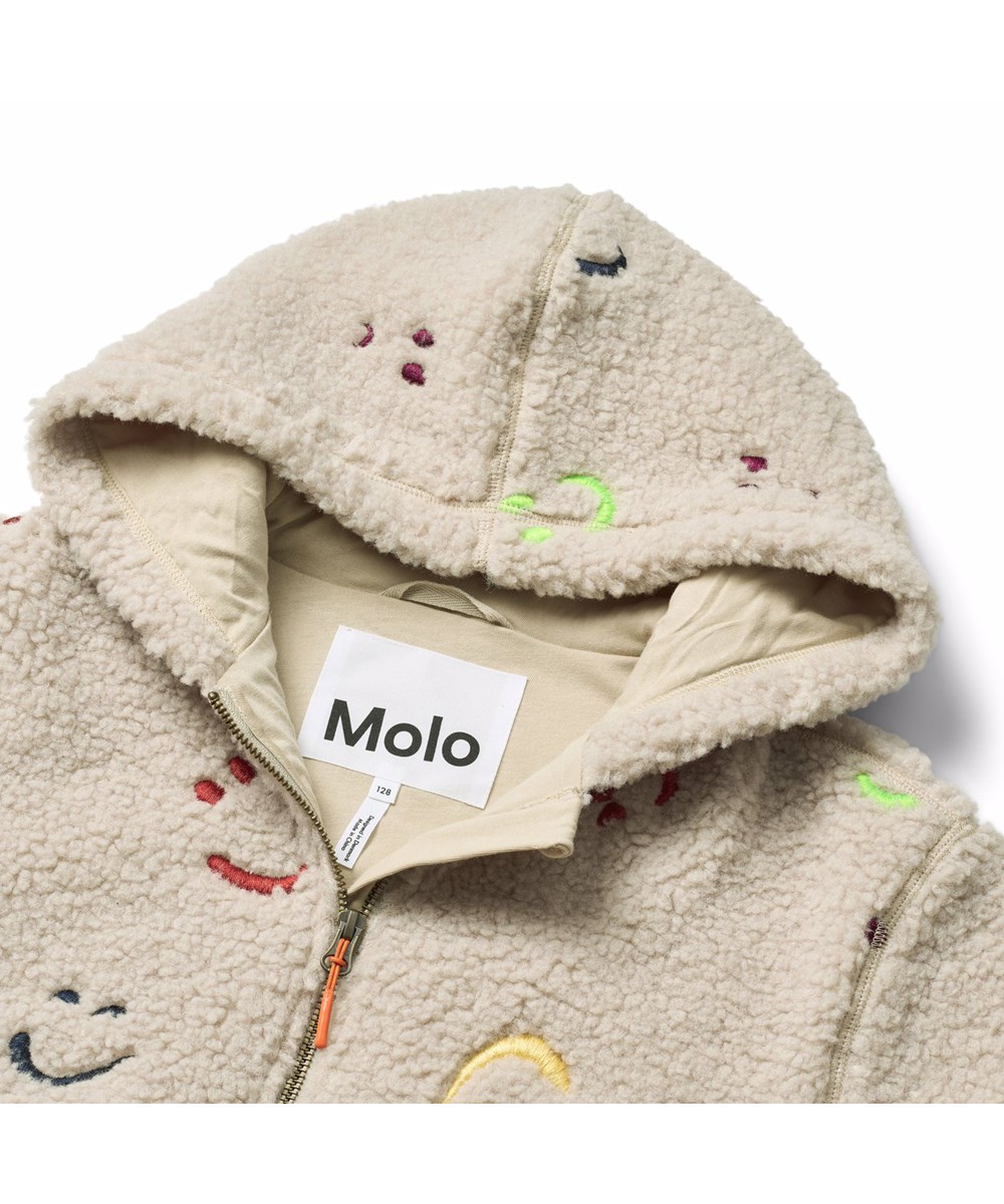 Hazzy - Teddy Emotions - Beige Fleecejacke für Kinder aus recyceltem Polyester mit gestickten bunten lächelnden Gesichtern.
