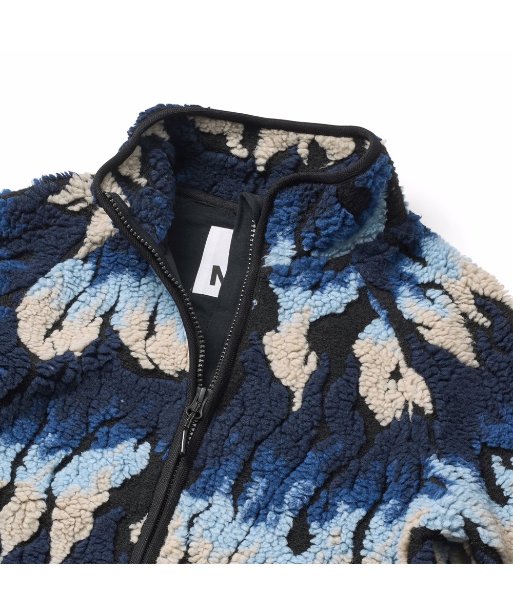 Unique - Ingenuity Cool - Weiche Fleecejacke für Kinder aus recyceltem Polyester mit passenden gerippten Abschlüssen und gefüttert mit weicher Baumwolle. Das Muster der Jacke erinnert an Flammen in Blau- und Beigetönen.