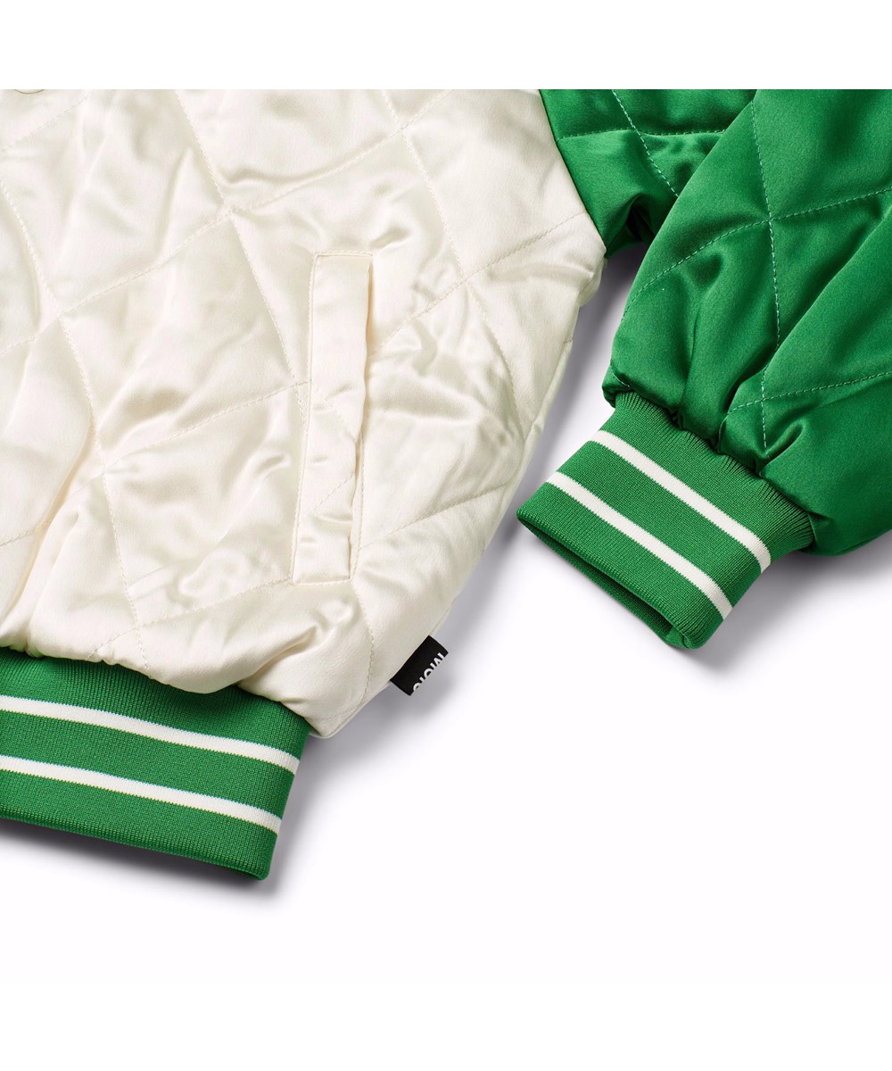 Haru - Jaguar And Snake - Gesteppte Bomberjacke für Kinder in Grün und Off-White mit einem bestickten Rückenpatch eines Geparden und einer Schlange in lebendigen Farben und dem Text "Forza Della Natura" auf der Brust.