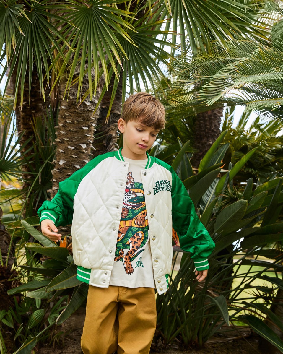 Haru - Jaguar And Snake - Gesteppte Bomberjacke für Kinder in Grün und Off-White mit einem bestickten Rückenpatch eines Geparden und einer Schlange in lebendigen Farben und dem Text "Forza Della Natura" auf der Brust.