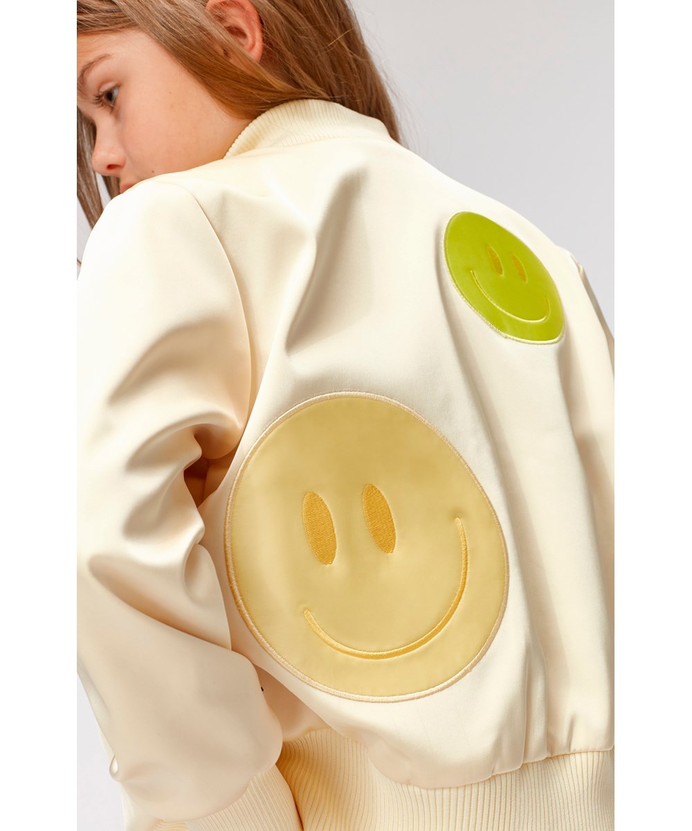 Hazel - Pearled Ivory - Gelbe Trainingsjacke mit Smiley-Patches.