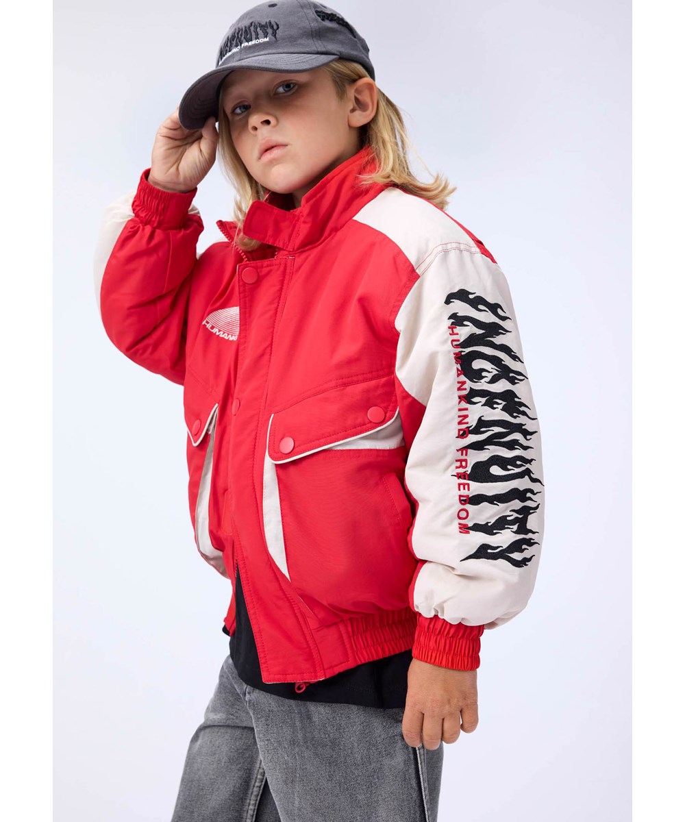 Herold - Vivid - Rote und weiße Jacke für Kinder mit einem bestickten Text auf der Rückseite und dem Ärmel, "Ingenuity humankind freedom".