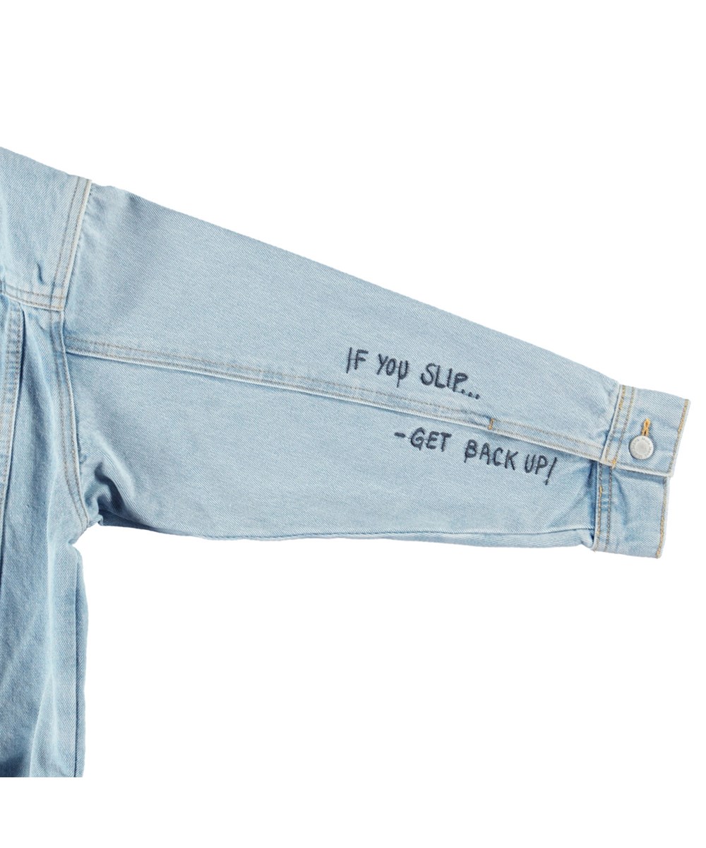 Honore - Sun-Bleach Blue - Hellblaue Jeansjacke für Kinder aus Baumwolle mit einer gestickten Bananenschale auf der Rückseite und dem Text auf dem Ärmel "If you slip.... Get back up".