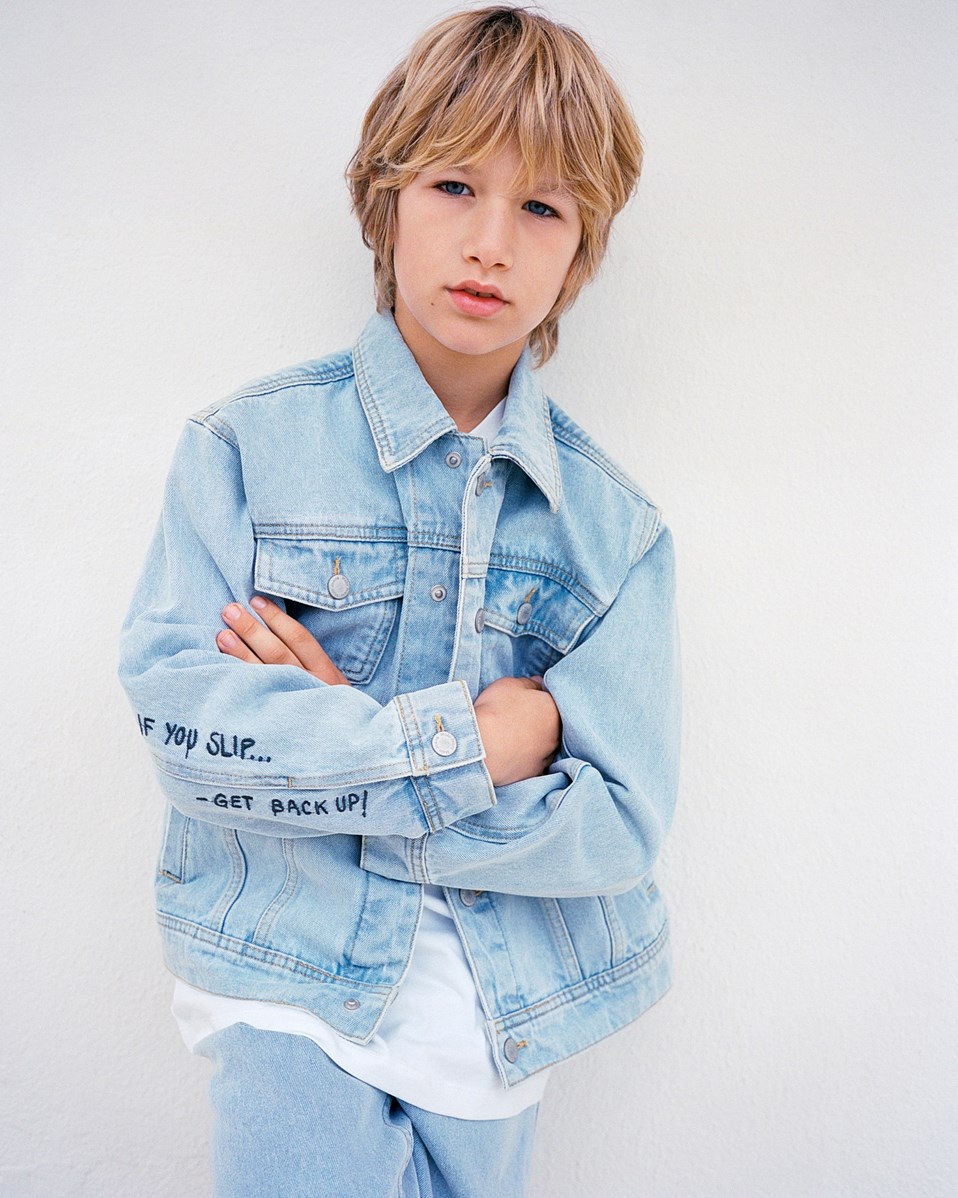 Honore - Sun-Bleach Blue - Hellblaue Jeansjacke für Kinder aus Baumwolle mit einer gestickten Bananenschale auf der Rückseite und dem Text auf dem Ärmel "If you slip.... Get back up".