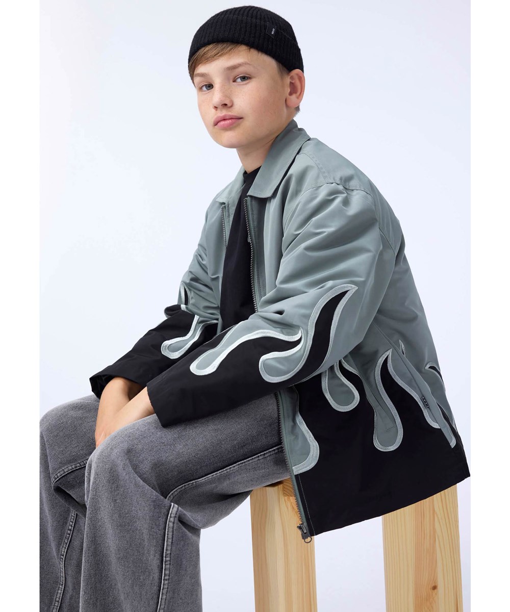 Hotson - Heated - Graue Jacke für Kinder mit schwarzen Flammen aus glänzendem Polyester.