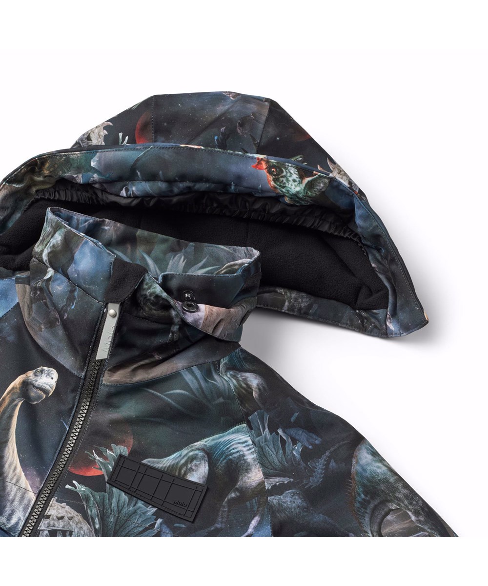 Castor - Dino In Space - Wind- und wasserdichte Winterjacke für Kinder aus recyceltem Polyester mit einem Druck von Dinosauriern im Weltraum in Blau-, Grün- und Brauntönen.