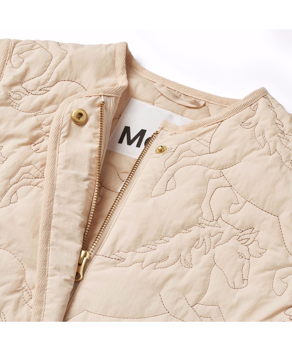 Holley - Brazilian Sand - Beige wasserabweisende Thermojacke für Kinder aus recyceltem Nylon mit einem gesteppten Muster von Pferden.