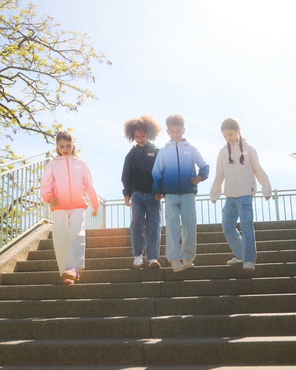 Horizon - Fade Pink - Wind- und wasserdichte Jacke für Kinder aus recyceltem Polyester mit einer Kapuze in pink und orange verlaufenden Farben.