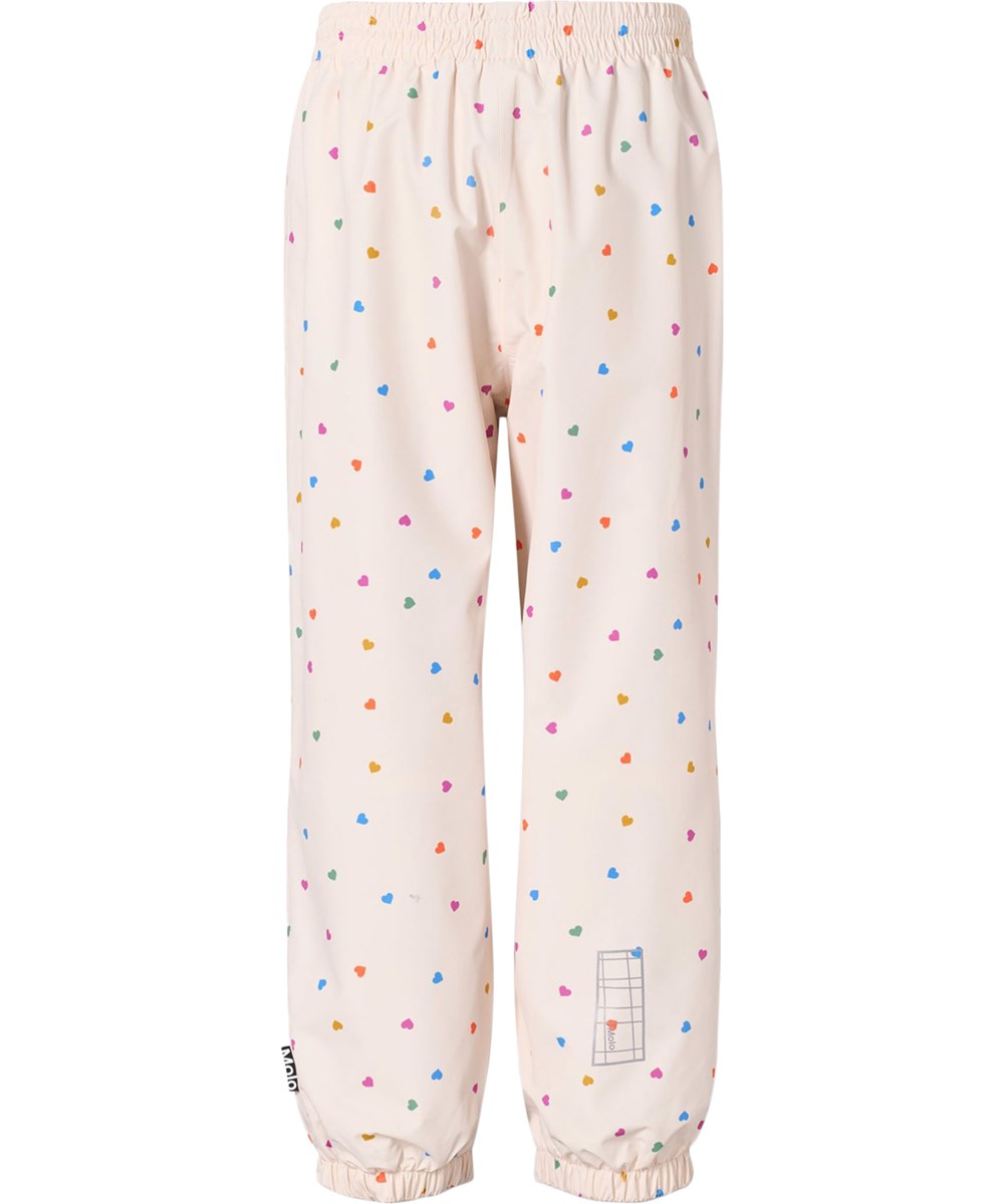 Waits - Confetti_Rainbow - Wasserdichte Regenhose aus recyceltem Polyester. Die Hose ist beige mit einem Druck von kleinen Herzen in verschiedenen Farben.