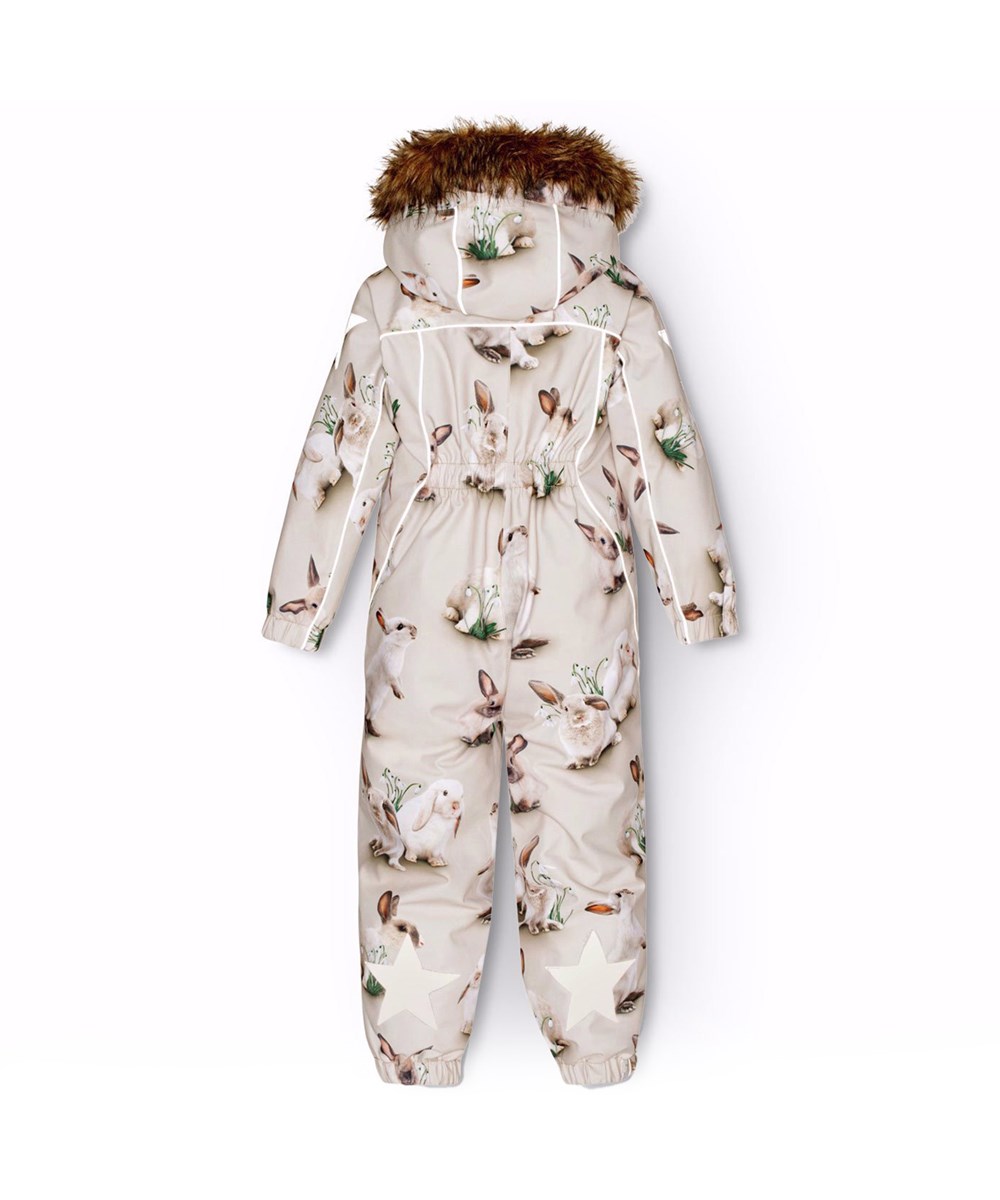 Polaris Fur - Winter Rabbits - Kinder-Schneeanzug aus recyceltem Polyester mit einem Druck von niedlichen Hasen zwischen Schneeglöckchen auf einem grauen Hintergrund.