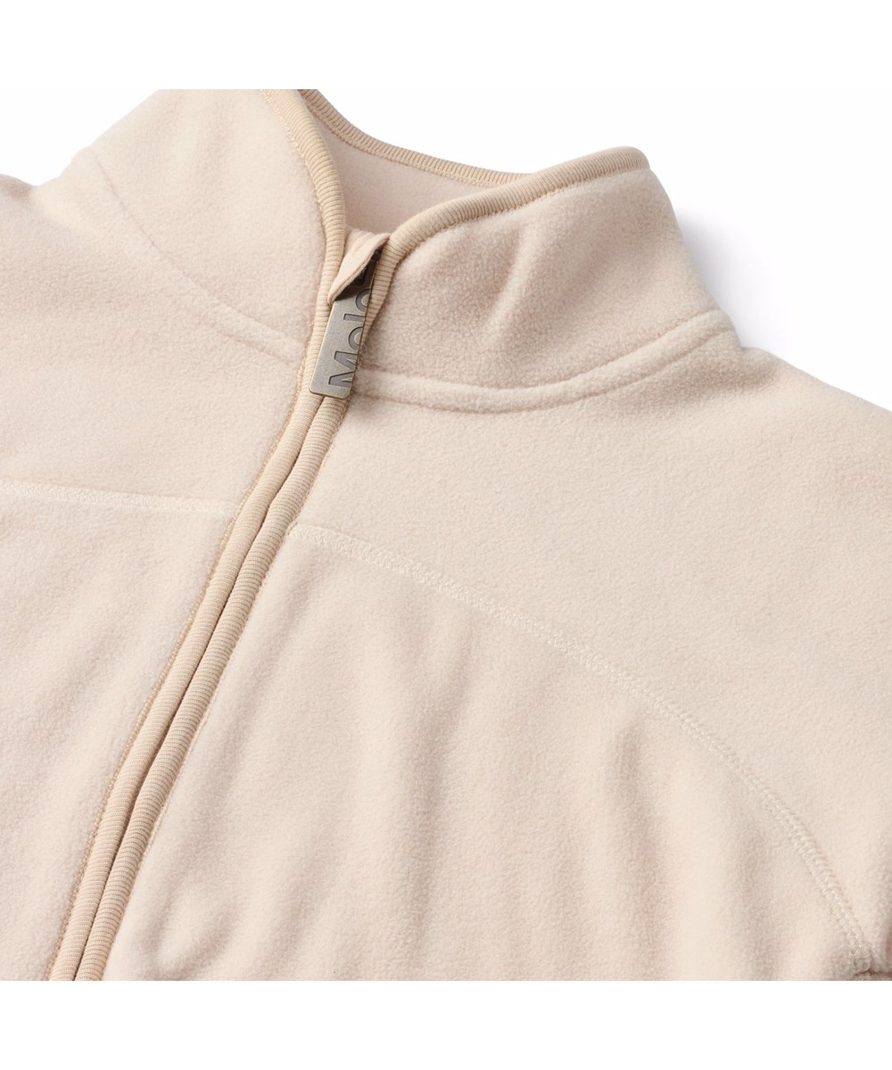 Ulani - Vanilla - Off-white fleece jacket for children made of recycled polyester with matching ribbed edges and a front pocket.