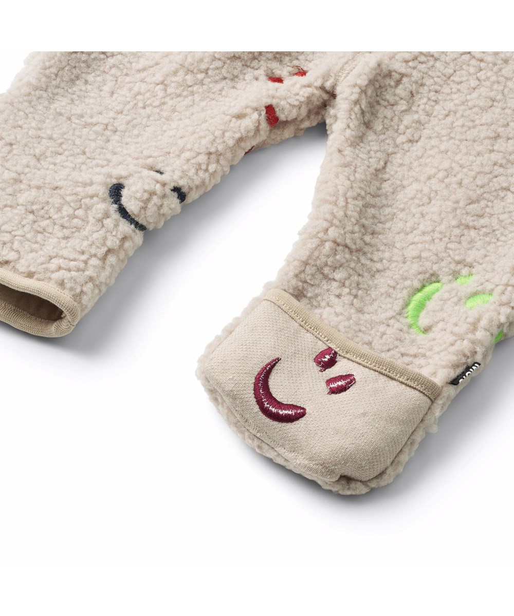 Umeko - Teddy Emotions - Beige fleece suit for the little ones in recycled polyester with border embroidered smiling faces in different colors and soft cotton lining.