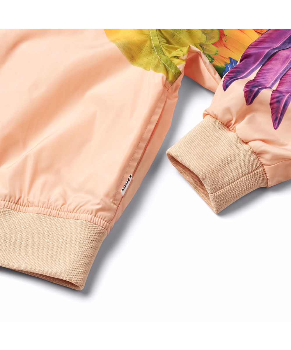 Haliva - Fantasy Parrots - Coral-coloured, water-repellent (PFC-free: PFOS and PFOA) bomber jacket for children in recycled polyester with a colourful print of parrots on the sleeves.