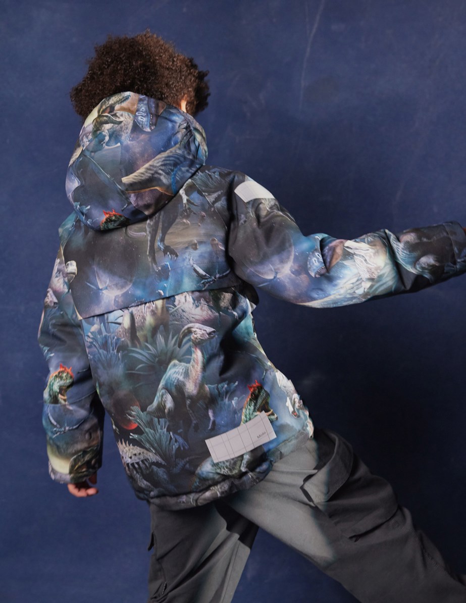 Castor - Dino In Space - Wind- and waterproof winter jacket for children in recycled polyester with a print of dinosaurs in space in shades of blue, green, and brown.