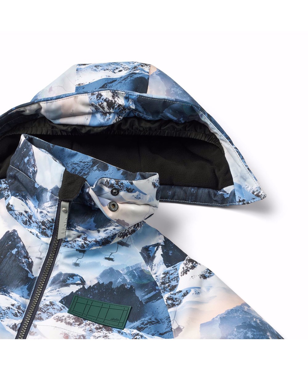 Castor - Mountain High - Wind- and waterproof winter jacket for children in recycled polyester with a print of a winter landscape in shades of blue.